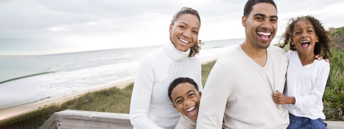 Happy smiling family in white sweaters near seashore